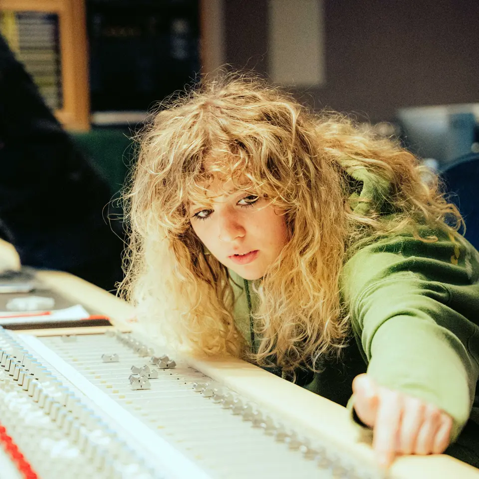 Fiona-Lee in Abbey Road studios leaning over a mixing desk to change a fader.